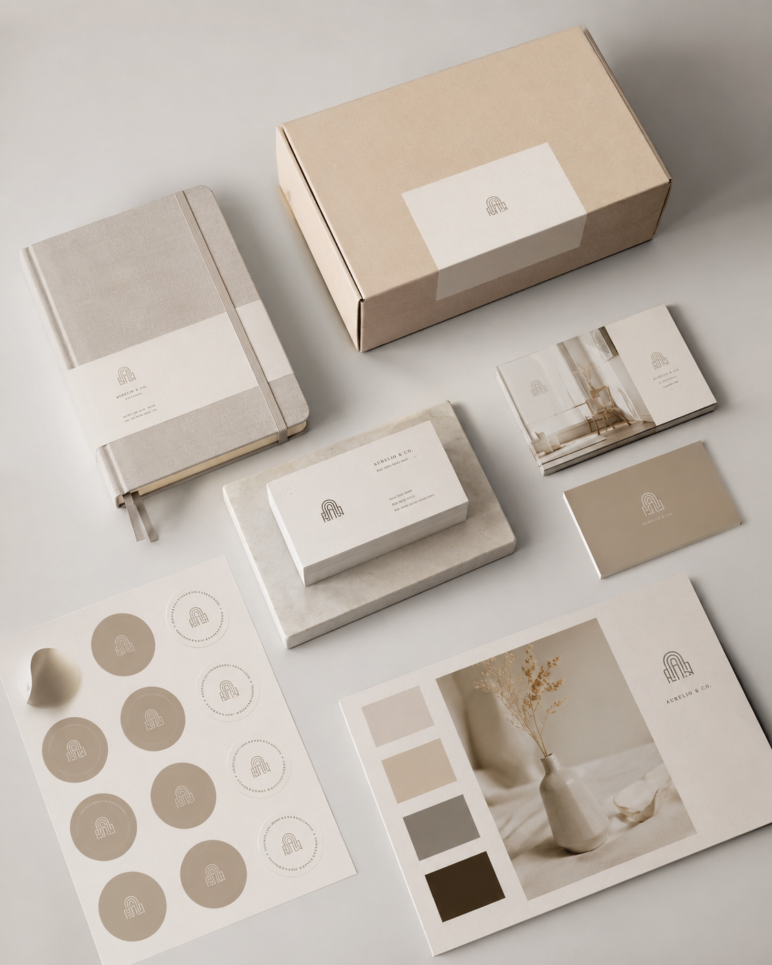 Luxe drukwerk en brandingmaterialen met visitekaartjes, stickers, verpakking en notitieboek op een lichte minimalistische achtergrond voor professionele huisstijlontwikkeling.